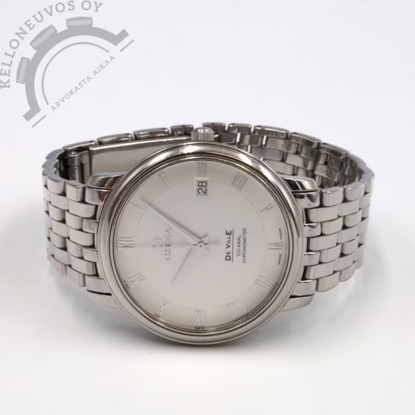 Tarjolle klassisen tyylikäs Omega De Ville. Selkeälukuisella hopeisella taululla jossa päivyri sekä roomalaiset indeksit. Kiillotettu teräksinen kuori jonka etupuolta suojaa safiirilasi. Kokonaisuuden kruunaa erittäin mukavan ranneistuvuuden omaava kuusirivinen kiillotettu teräsranneke. Teräksisen takakannen alla tikkaa erittäin tarkoin käyntiarvoin Omega 2500 -automaattikoneisto. Kelloa seuraa Omegan huoltoboksi ja käyntitesti tulokset. Rannekkeessa mittaa noin 18,5cm ranteelle. Takakannessa kevyt kaiverrus joka huomioitu hinnassa.